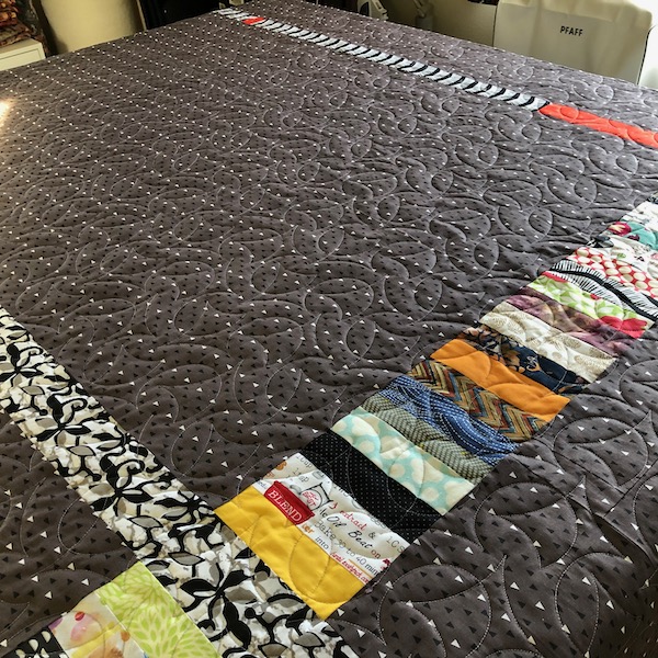 Pieced quilt back highlights Calder edge to edge quilting design